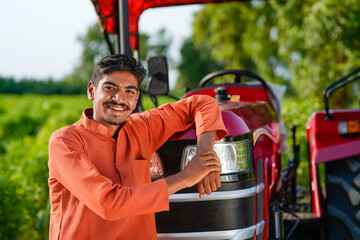indian farmer standing with tractor at field