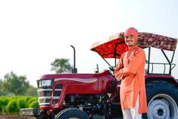 indian farmer standing with tractor at field