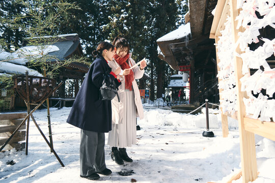 神社でおみくじを見せ合う日本人女性