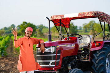 indian farmer standing with tractor at field