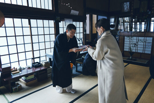 伝統的な日本寺院で御朱印帳を手渡す僧侶