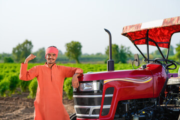 indian farmer standing with tractor at field
