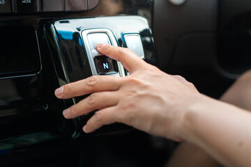 A driver is press on electrical A/T gear shifter button of the modern car. Transportation in action...
