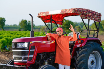 indian farmer standing with tractor at field