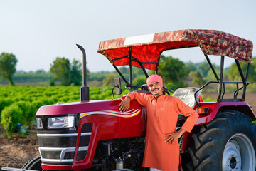 indian farmer standing with tractor at field