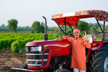 indian farmer standing with tractor at field