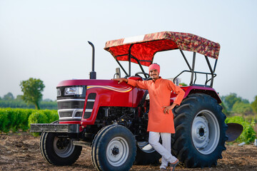 indian farmer standing with tractor at field