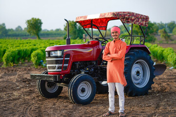 indian farmer standing with tractor at field