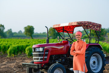 indian farmer standing with tractor at field