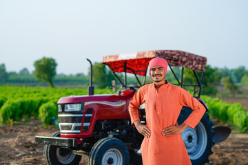 indian farmer standing with tractor at field