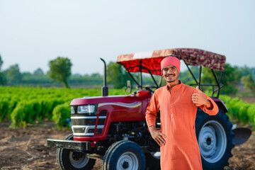 indian farmer standing with tractor at field