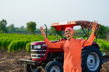 indian farmer standing with tractor at field