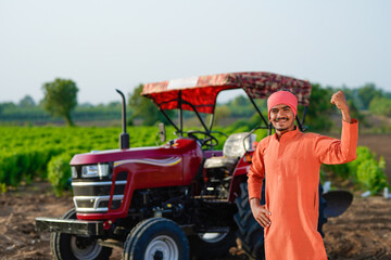 indian farmer standing with tractor at field
