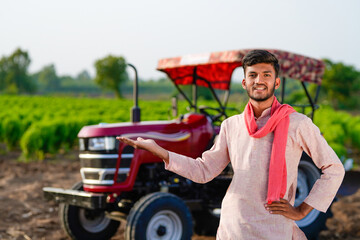 indian farmer standing with tractor at field