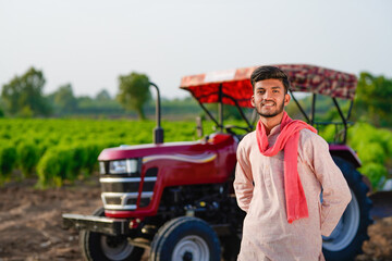 indian farmer standing with tractor at field