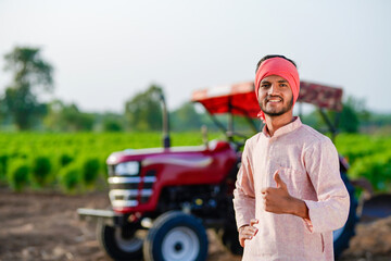 indian farmer standing with tractor at field