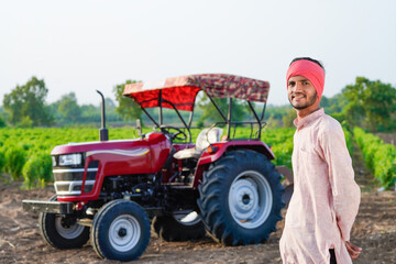 indian farmer standing with tractor at field