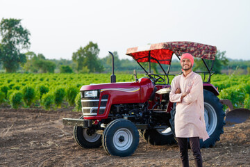 indian farmer standing with tractor at field