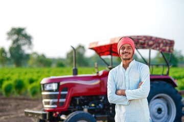 indian farmer standing with tractor at field