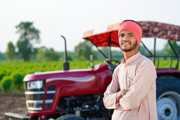 indian farmer standing with tractor at field