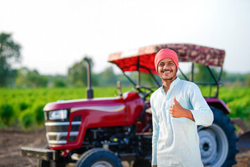 indian farmer standing with tractor at field