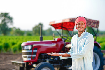 indian farmer standing with tractor at field