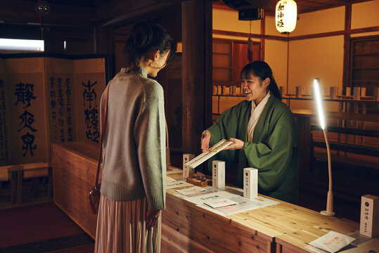 神社で巫女さんからお札を受け取る日本人女性