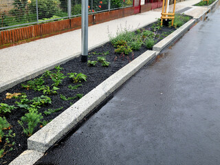 Water from the road is absorbed through the gaps in the curb and the slope of the asphalt towards the edge. Perennial flower beds absorb water for growth. Mulching with gravel
