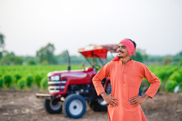 indian farmer standing with tractor at field