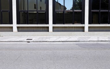 Modern building with large windows at the roadside. Sidewalk and street in front. Background for...