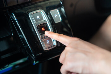 A driver is press on electrical A/T gear shifter button of the modern car. Transportation in action...