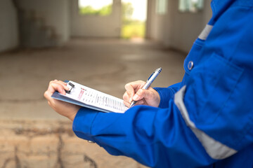 A construction foreman is checking on building quality checklist report during inspecting at the...