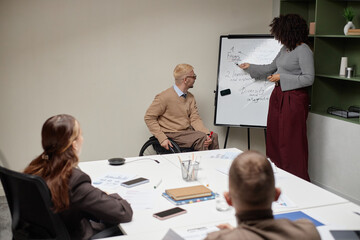 Diverse group of young adult professionals attending business meeting, Black woman presenting...