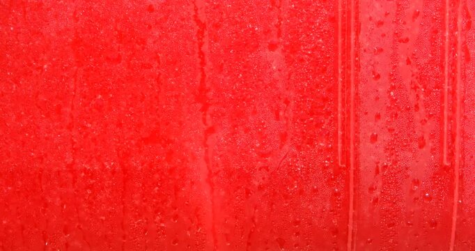Drops of condensation on the red ice cream tank. Ice cold sorbet machine mixing fruit juice. Freezing slush spinning around, summer treat.