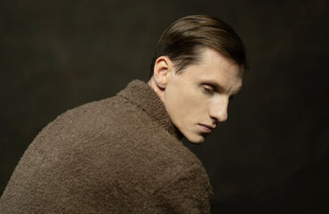 Stylish thoughtful young man in brown sweater.