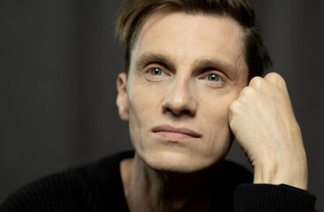 Close-up portrait of stylish handsome young man posing on dark background.