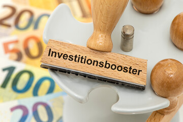 Ein Holzstempel ist beschriftet mit dem Aufdruck Investitionsbooster