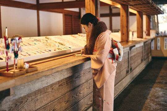 神社で絵馬に願い事を書く日本人女性
