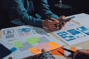 Group of young application developers analyzing uxui mobile app templates during a working meeting