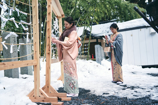 神社でおみくじを結ぶ着物姿の日本人女性