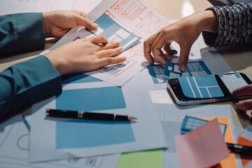 Group of young application developers analyzing uxui mobile app templates during a working meeting