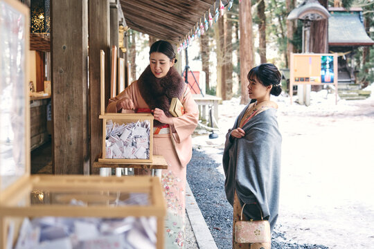 神社でおみくじを引く着物姿の日本人女性