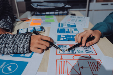 Group of young application developers analyzing uxui mobile app templates during a working meeting