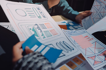 Group of young application developers analyzing uxui mobile app templates during a working meeting