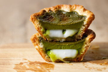 Closeup of Matcha and mochi Portuguese sweet dessert egg tart or Pastel de Nata on wooden board on...