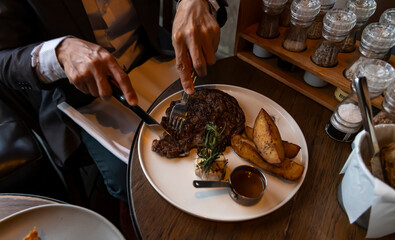 Man hand cut of Grilled Steak for dinner meal in the restaurant