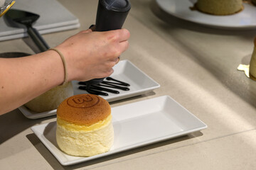 Close-up of fluffy Japanese cheesecakes with golden tops, displayed in a bakery showcase, ready for sale.