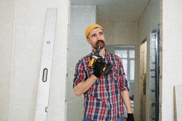 construction worker guy with a drill on a white wall background.master for an hour.