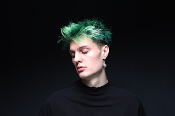 Studio portrait of a young male model with green hair on a black background