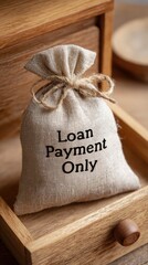 Burlap sack labeled "Loan Payment Only" tied with a string, placed inside a wooden drawer.